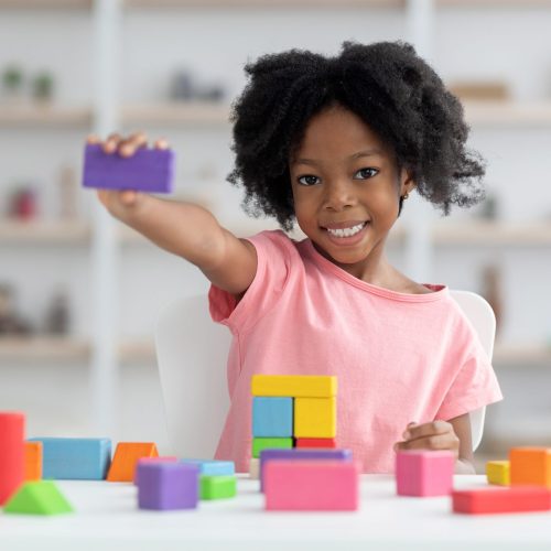 cute-little-black-girl-showing-purple-wooden-block-scaled-1.jpg